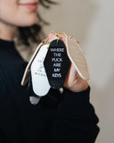Hand holding assorted motel-style keychains including the I'll Get Gas in the Morning Keychain