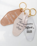 Hand holding assorted motel-style keychains including the Always Late but Worth the Wait Keychain