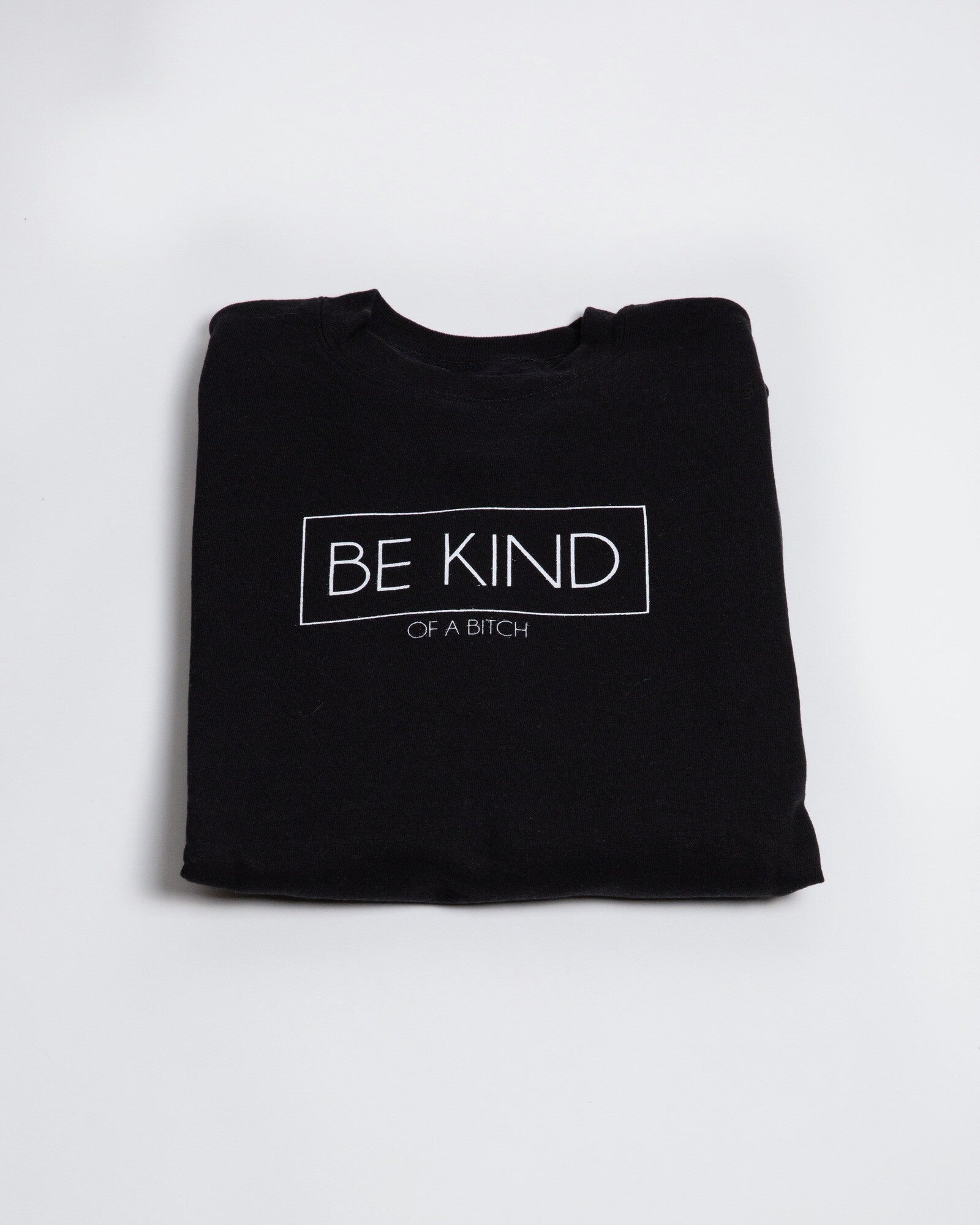 Folded black Be Kind of a Bitch crewneck on a light background.