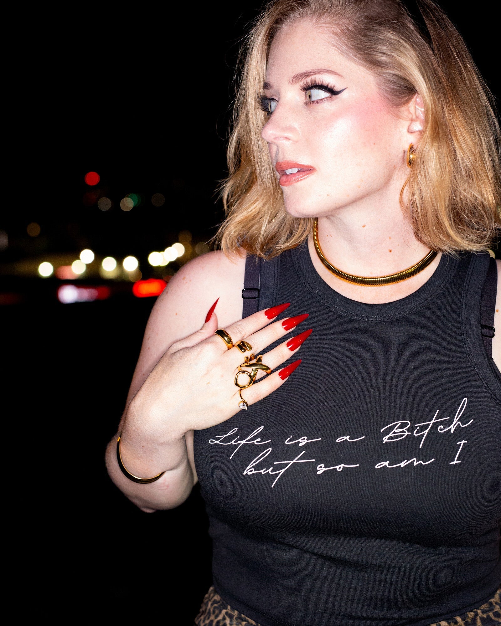 Model wearing the black Life’s a Bitch tank in a nighttime close-up.