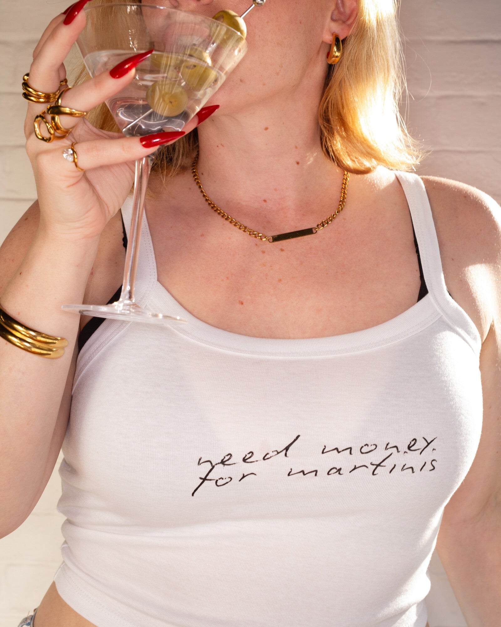 Model wearing the white Need Money for Martinis cami tank while holding a martini glass.