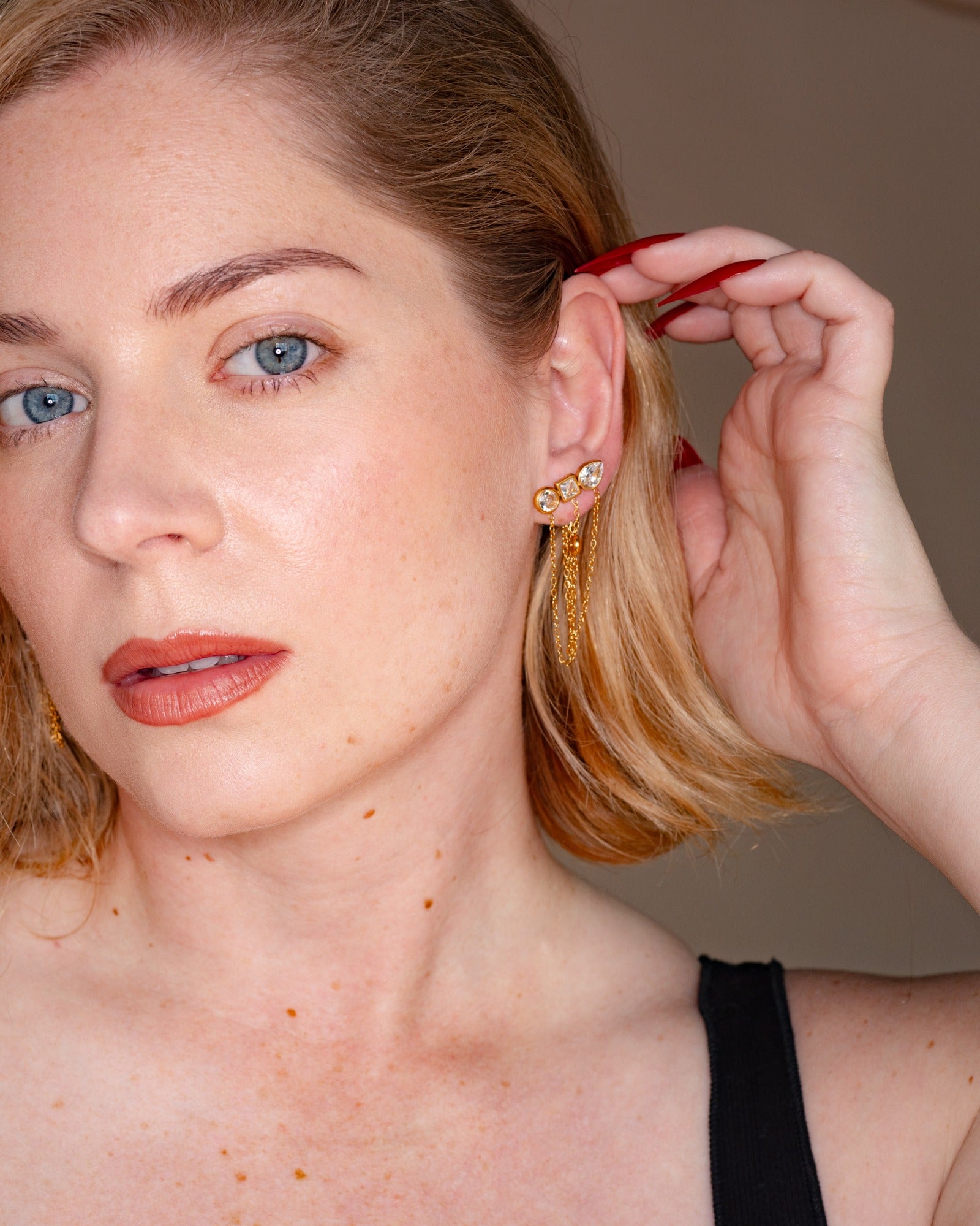 Ariadne chain tassel earring worn at the ear in a close-up portrait.