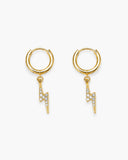 Pair of polished gold-tone huggie earrings with clear stone lightning bolt charms on a white background.
