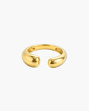 Polished gold-tone Atalanta open bypass ring with a smooth curved band and two rounded sculptural ends on a white background.