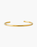 Athena Cuff 18K Gold PVD open cuff bracelet on a gray background.