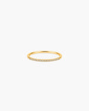 Slim polished gold-tone Aura stacking ring with a delicate row of clear pavé-style stones.