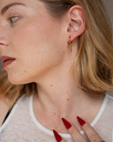 Ava gold hoop and bar drop earring worn in a close side portrait.