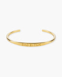 Gold open cuff bracelet engraved with BAD BITCH on a white background.