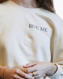 Cream crewneck sweatshirt with black text reading Bite Me on the front.