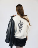 Back of a cream Bite Me crewneck sweatshirt with a large black serpent graphic.