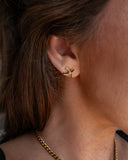 Buffy crossed gold stud worn in a close ear detail.