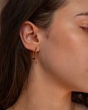 Circe rectangular gold hoop worn in a close-up ear detail.