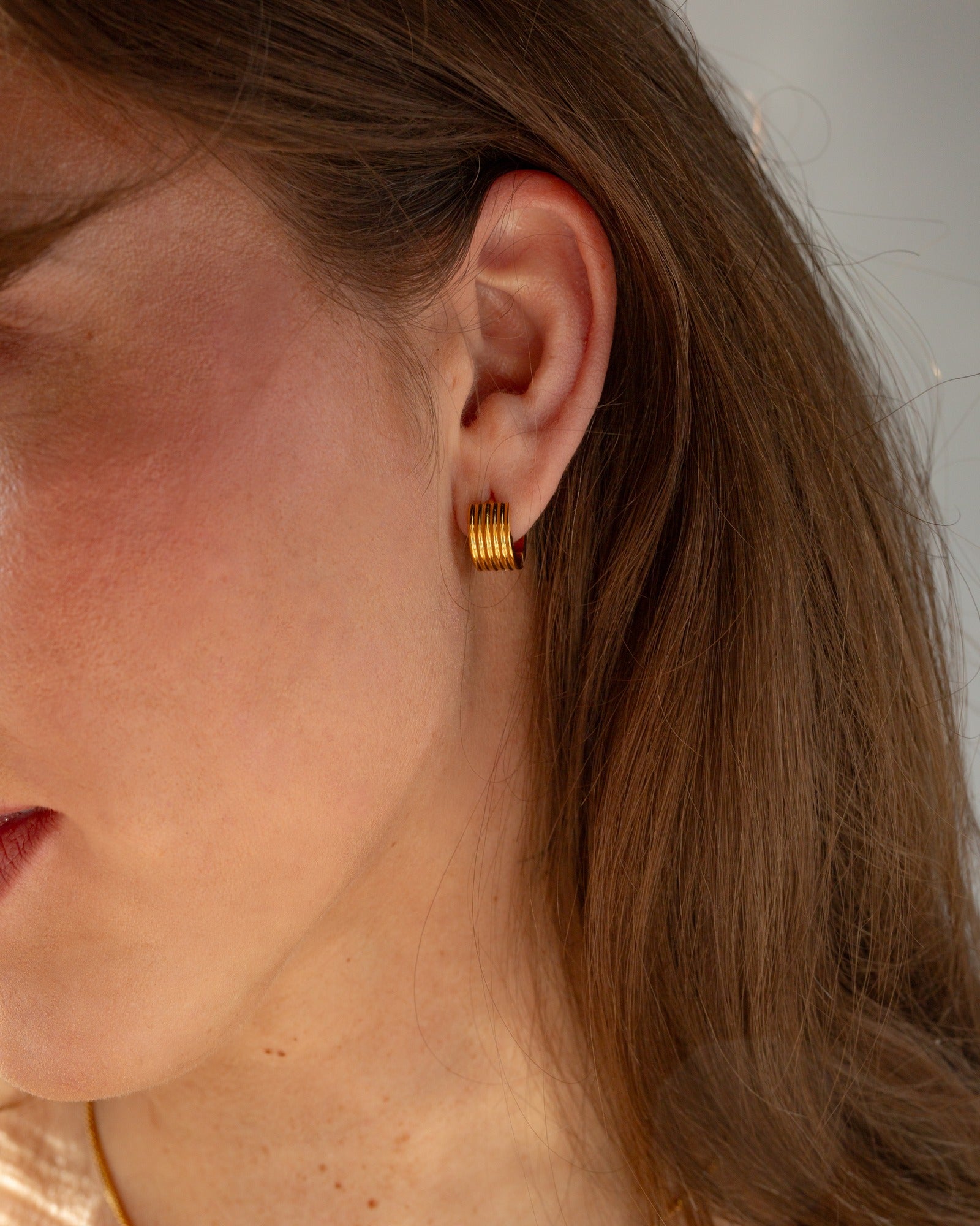 Cleo ridged gold huggie worn close to the ear.