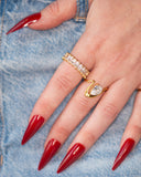 Davina sideways pear ring styled beside clear-stone bands on a hand with red nails against blue denim.