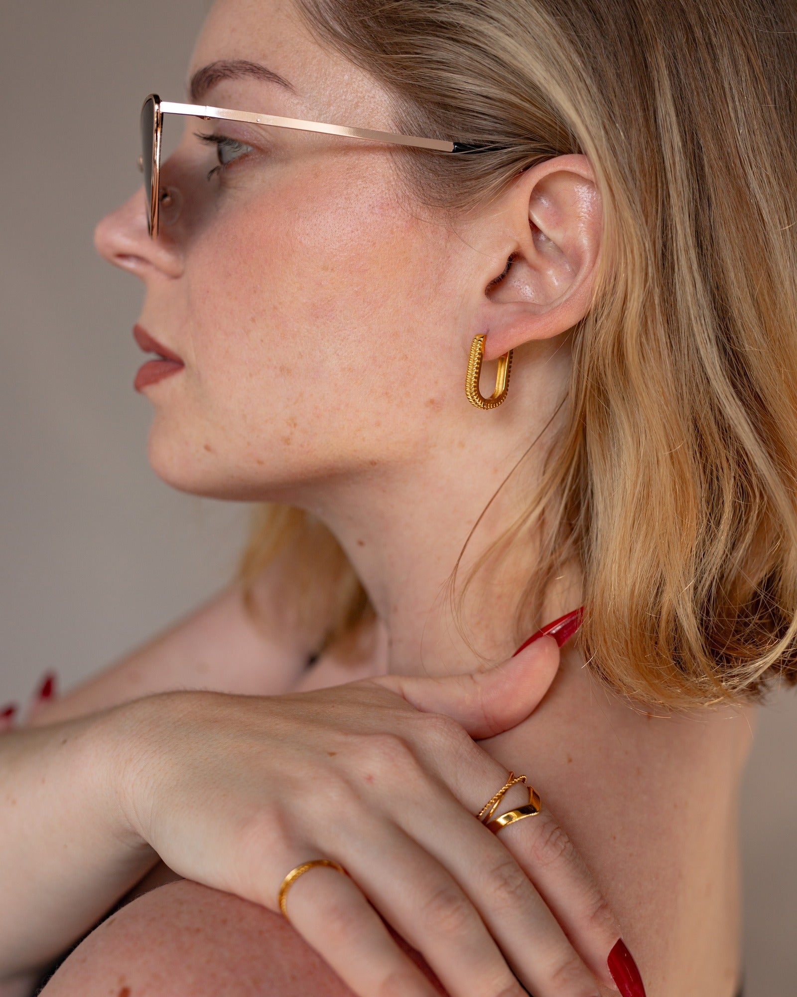 Electra rectangular gold hoop worn in a polished side portrait.
