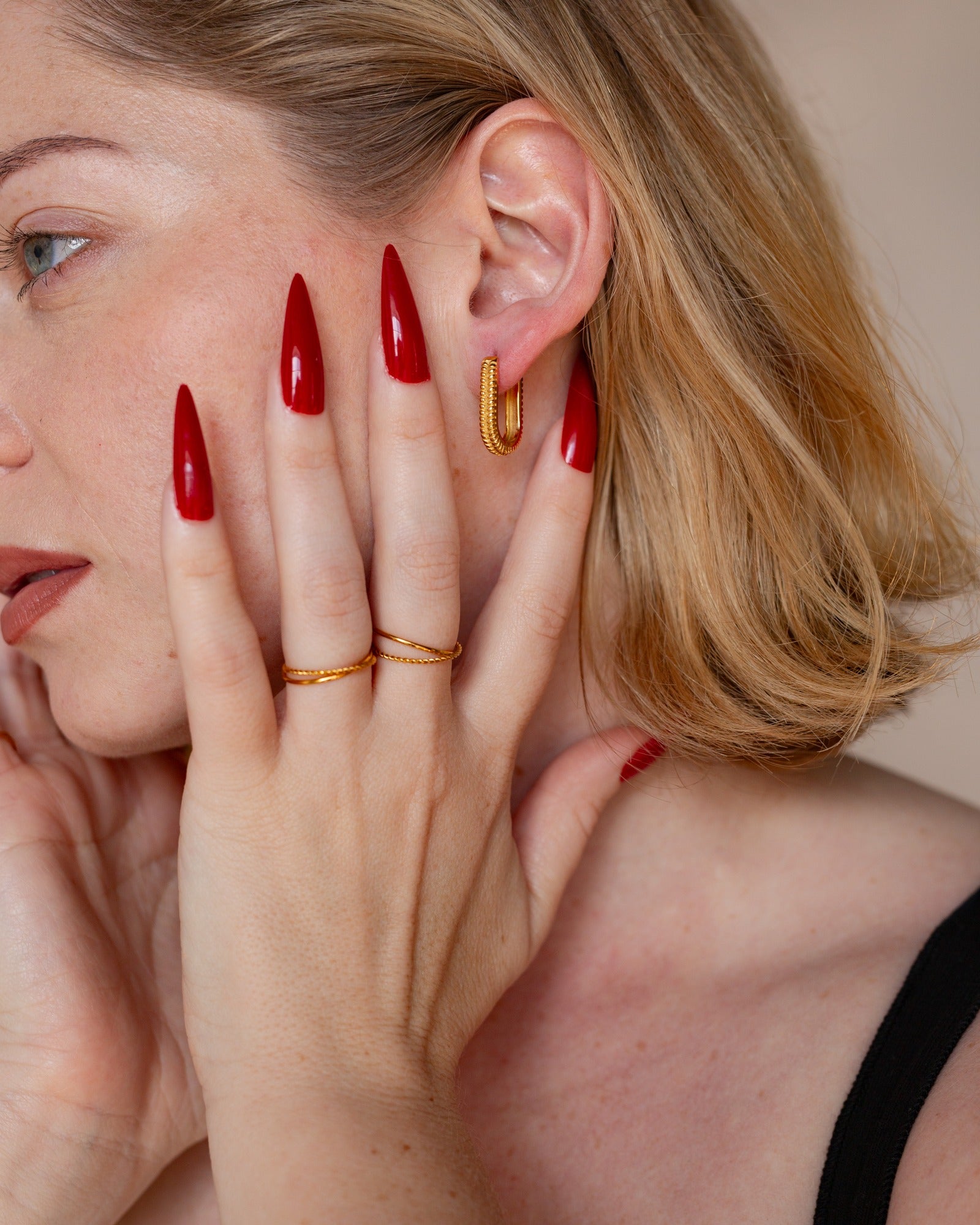 Electra textured rectangular earring shown in a close ear and hand detail.