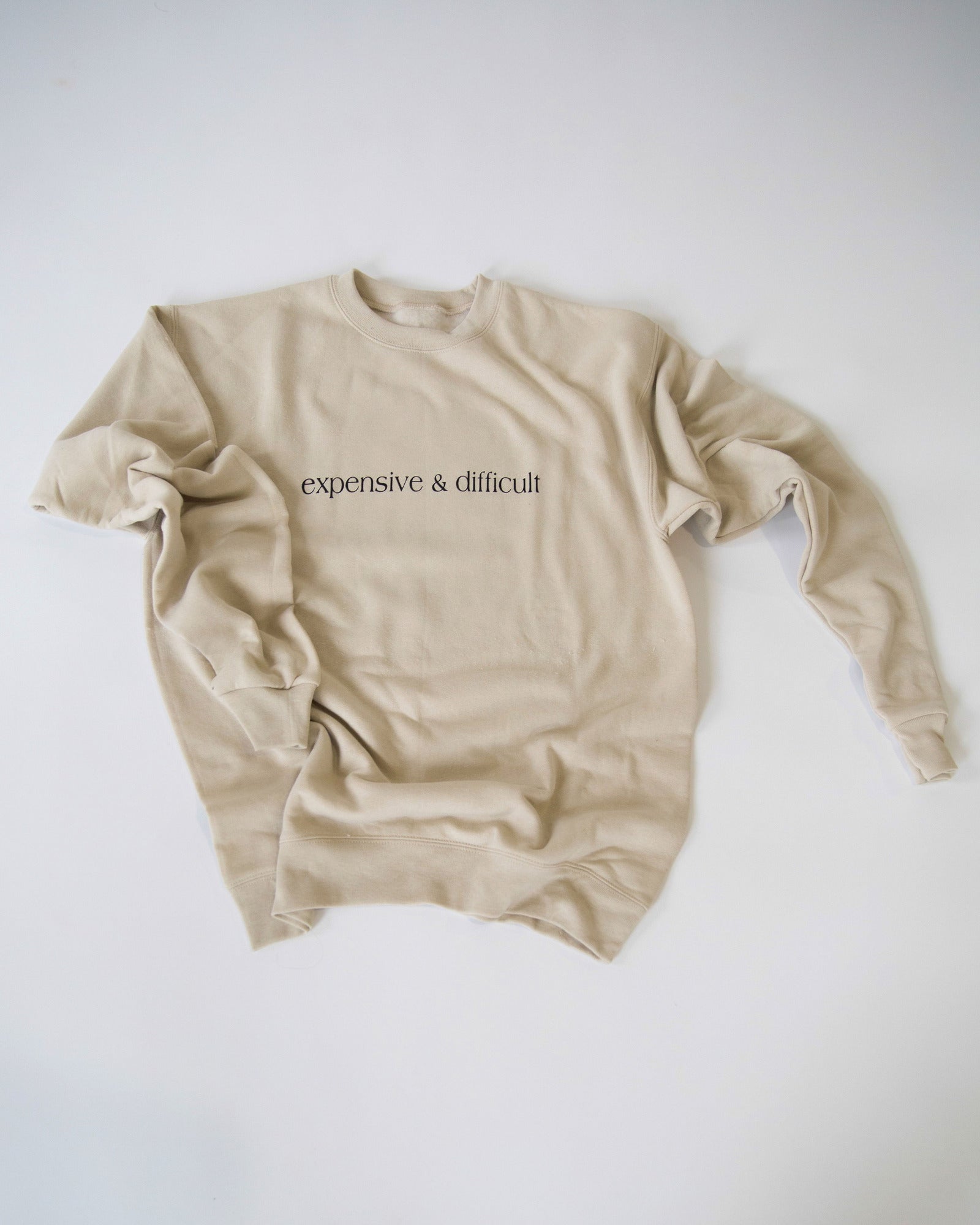 Cream Expensive and Difficult crewneck sweatshirt arranged on a white background.