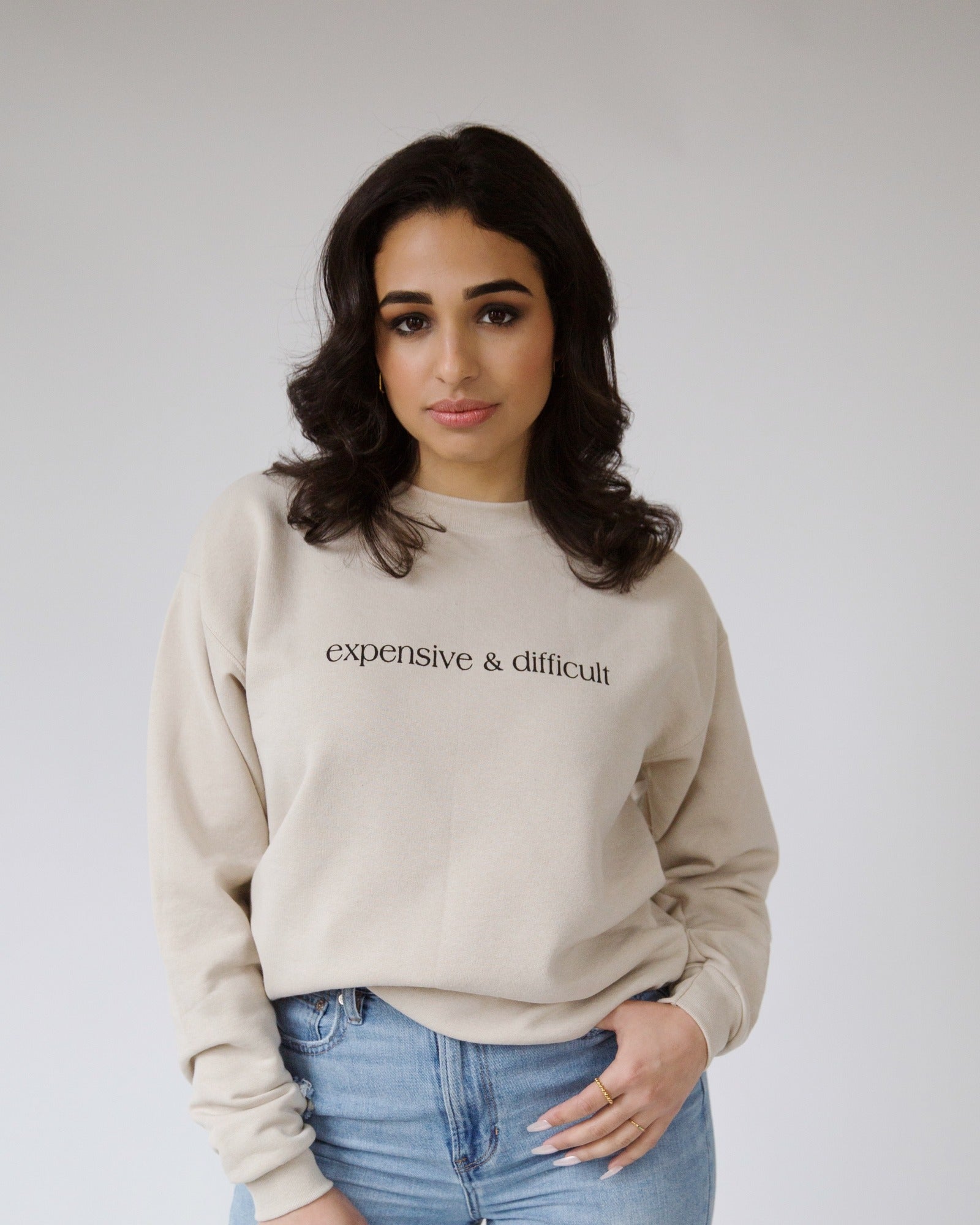Woman wearing the cream Expensive and Difficult crewneck sweatshirt.