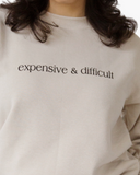 Cream crewneck sweatshirt with black text reading expensive & difficult across the chest.