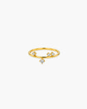 Slim gold-tone Helen ring with scattered clear stones and one dangling center stone on a white background.