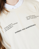 Cream crewneck sweatshirt with high maintenance warning text across the front.