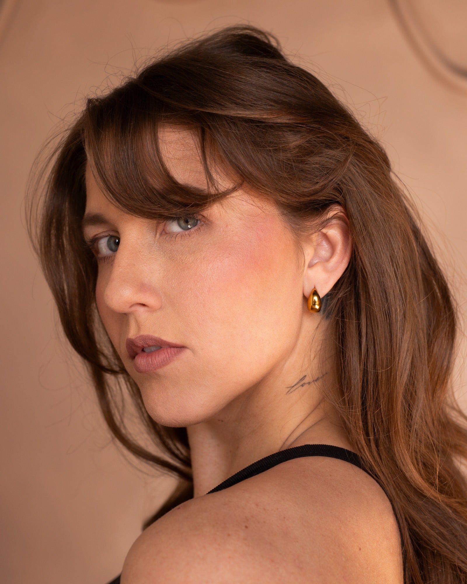 Jackie gold huggie styled in a close lifestyle portrait.