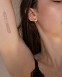 Josephine baguette stone gold huggie worn in a close-up portrait.