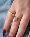 Liza emerald-cut stone band shown in a close hand detail beside a pear-shaped clear-stone ring.