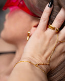 Lyra geometric open gold ring worn with long black nails and a delicate hand chain in a red-visor portrait.