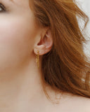 Melinoe layered chain dangle earring worn in a close ear detail.
