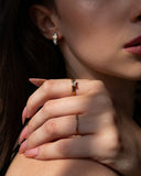 Nelle east-west emerald-cut ring worn with pale pink nails in a close hand-on-shoulder portrait.