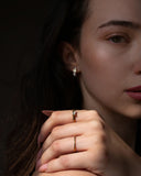 Nelle rectangular clear-stone ring styled in a dark close portrait with pale pink nails.