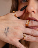 Noor clear-stone bypass ring worn with black nails in a tight hand-to-face detail.