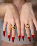 O Ring worn on hand beside a sculptural gold statement ring with red nails.