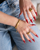 Octavia polished gold dome ring styled with layered rings and long red nails against blue denim.