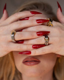 Piper beaded safety-pin ring worn with red nails in a tight hands-across-face detail.