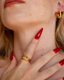 Reina gold chevron stacking ring worn with long red nails in a close hand-to-neck portrait.