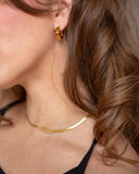 Rhea rounded square gold hoop worn in a close-up portrait.