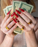 Rich Bitch engraved gold ring styled with red nails and dollar bills.