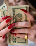 Rich Bitch engraved ring styled with red nails and cash in a close hand detail.