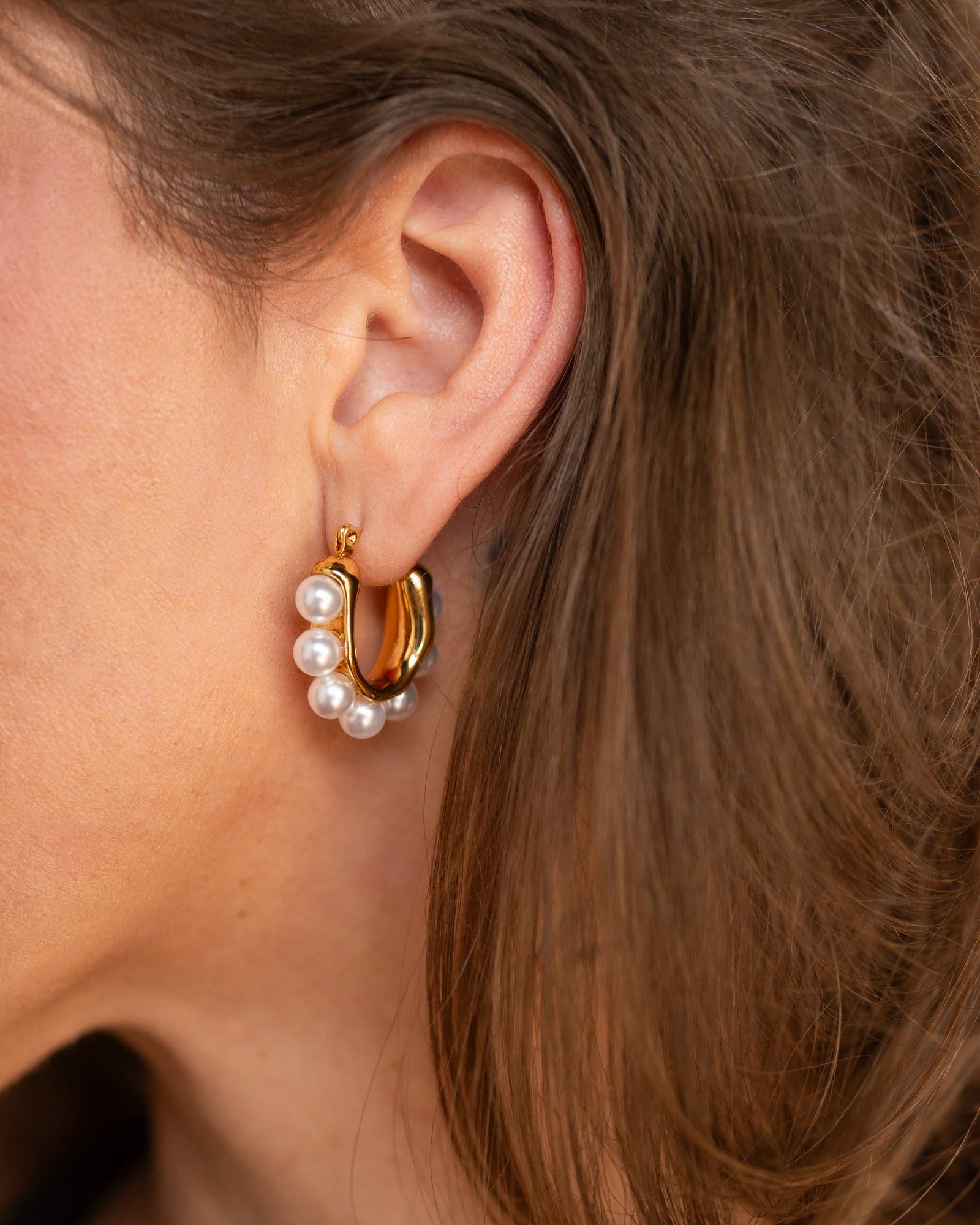Shiv gold pearl statement hoop worn in a close ear detail.