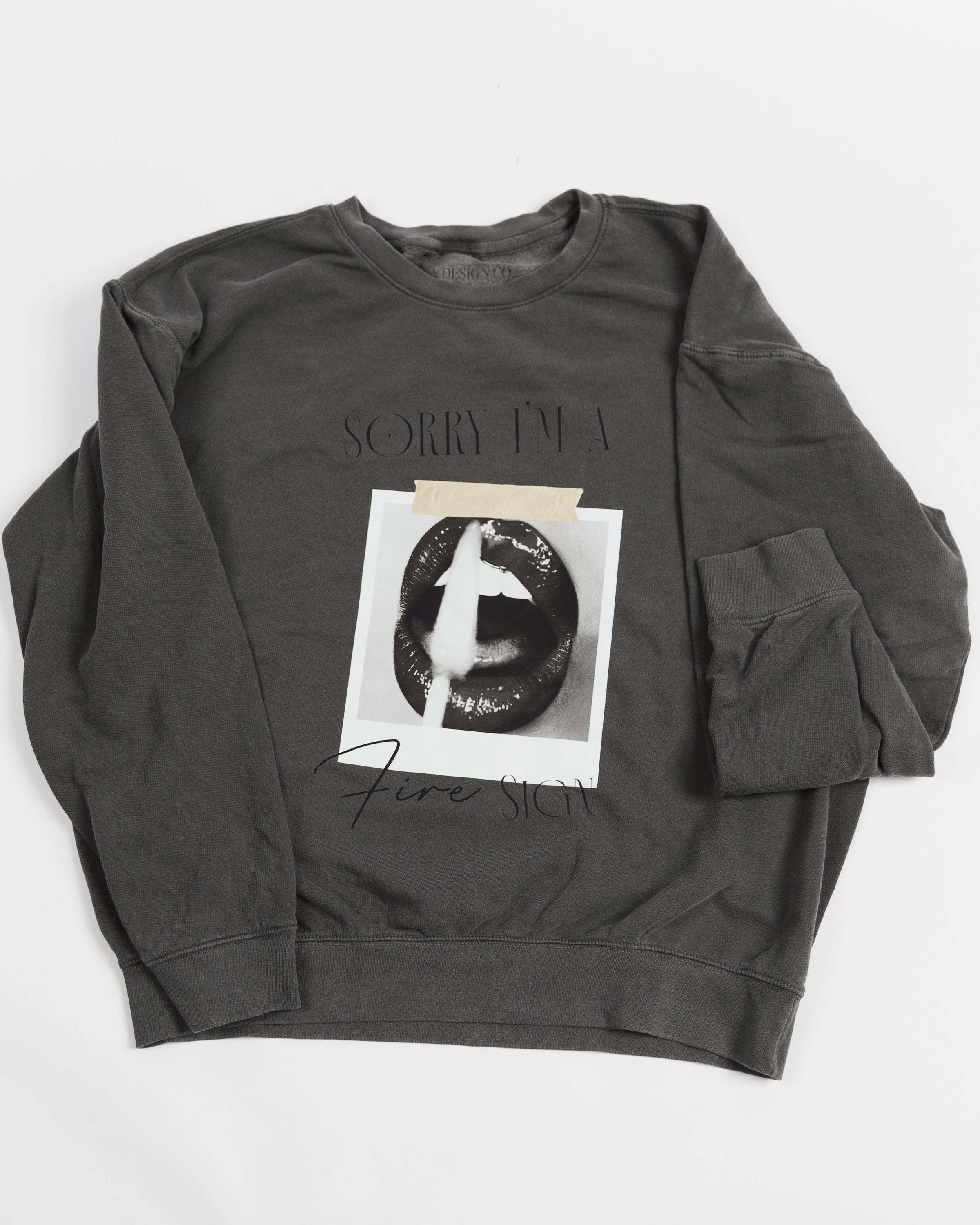 Washed charcoal Sorry I’m a Fire Sign crewneck sweatshirt laid flat.