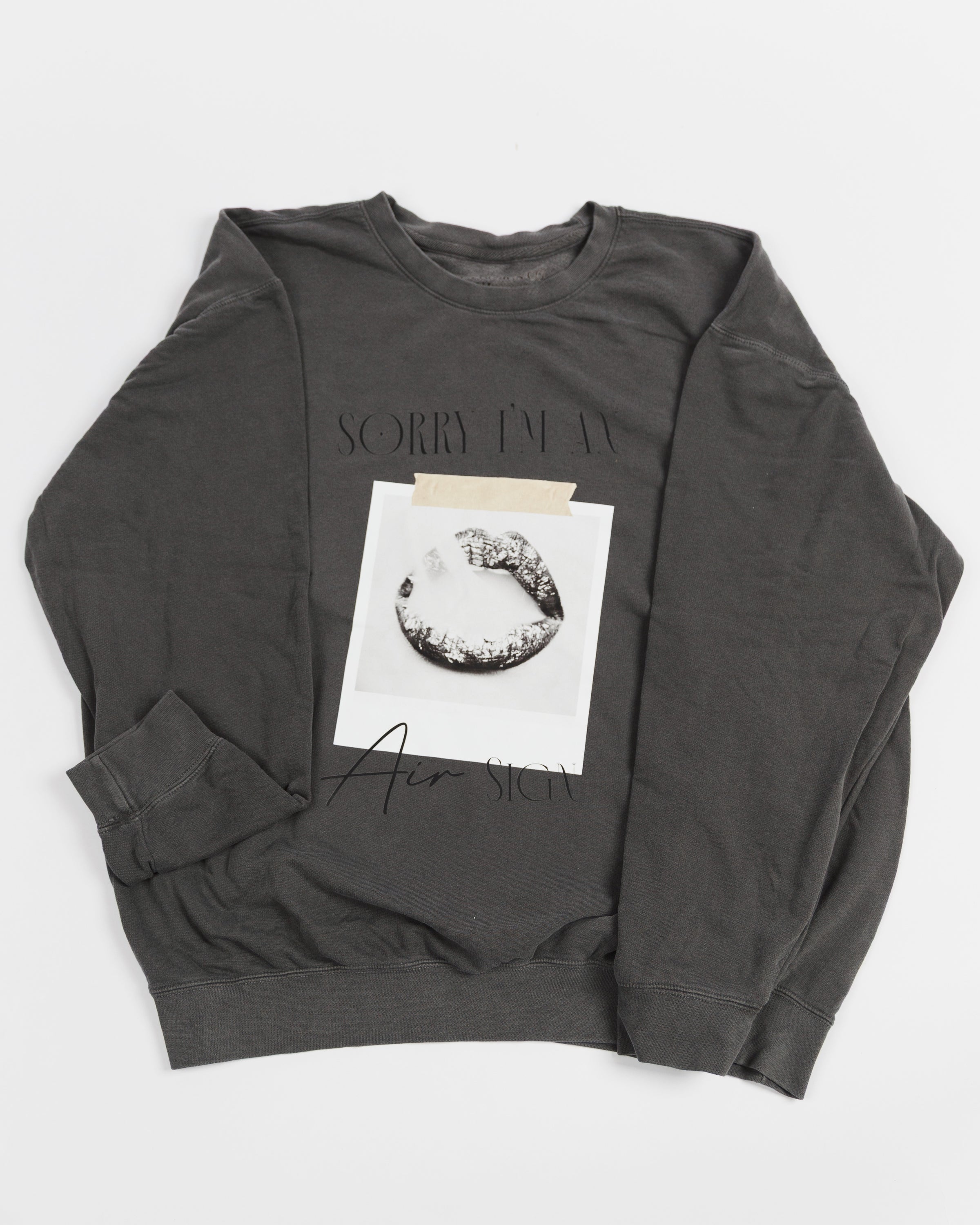 Washed charcoal Sorry I’m an Air Sign crewneck sweatshirt laid flat.