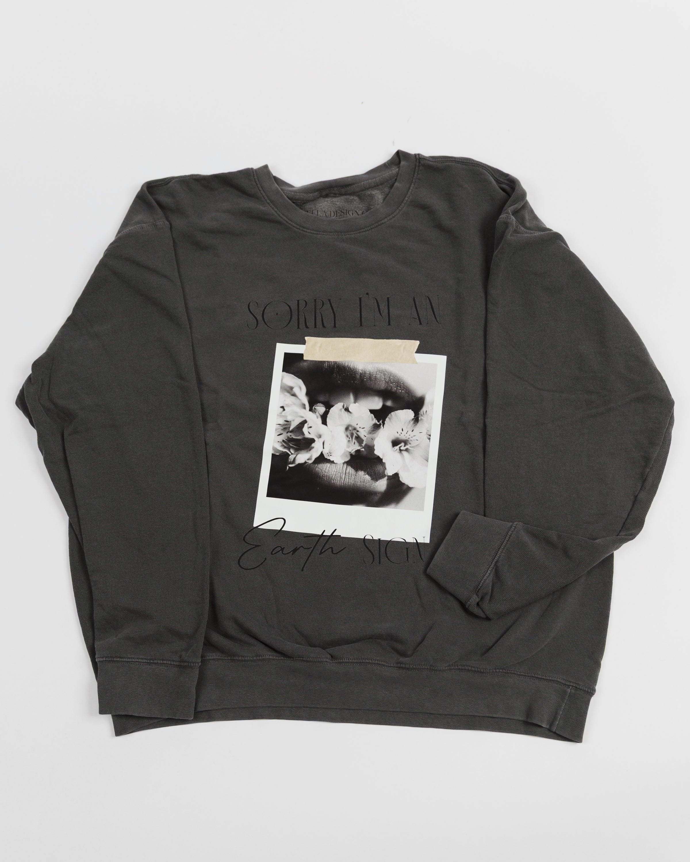 Washed charcoal Sorry I’m an Earth Sign crewneck sweatshirt laid flat.