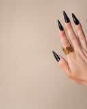 Vivi organic ridged gold ring displayed on an upright hand with long black nails.
