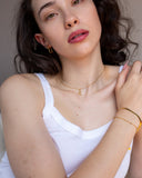 Gold zodiac necklace worn at the neckline, hover view.